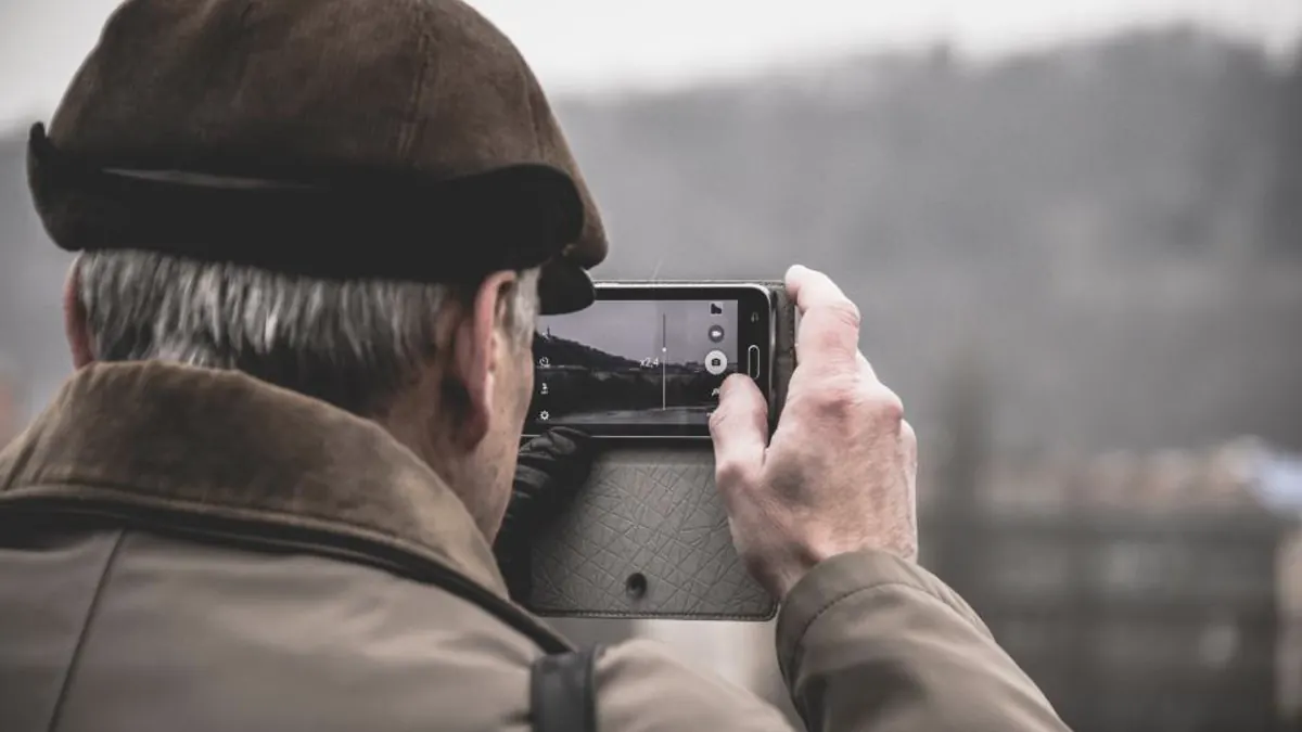 Пожилой мужчина фотографирует на телефон